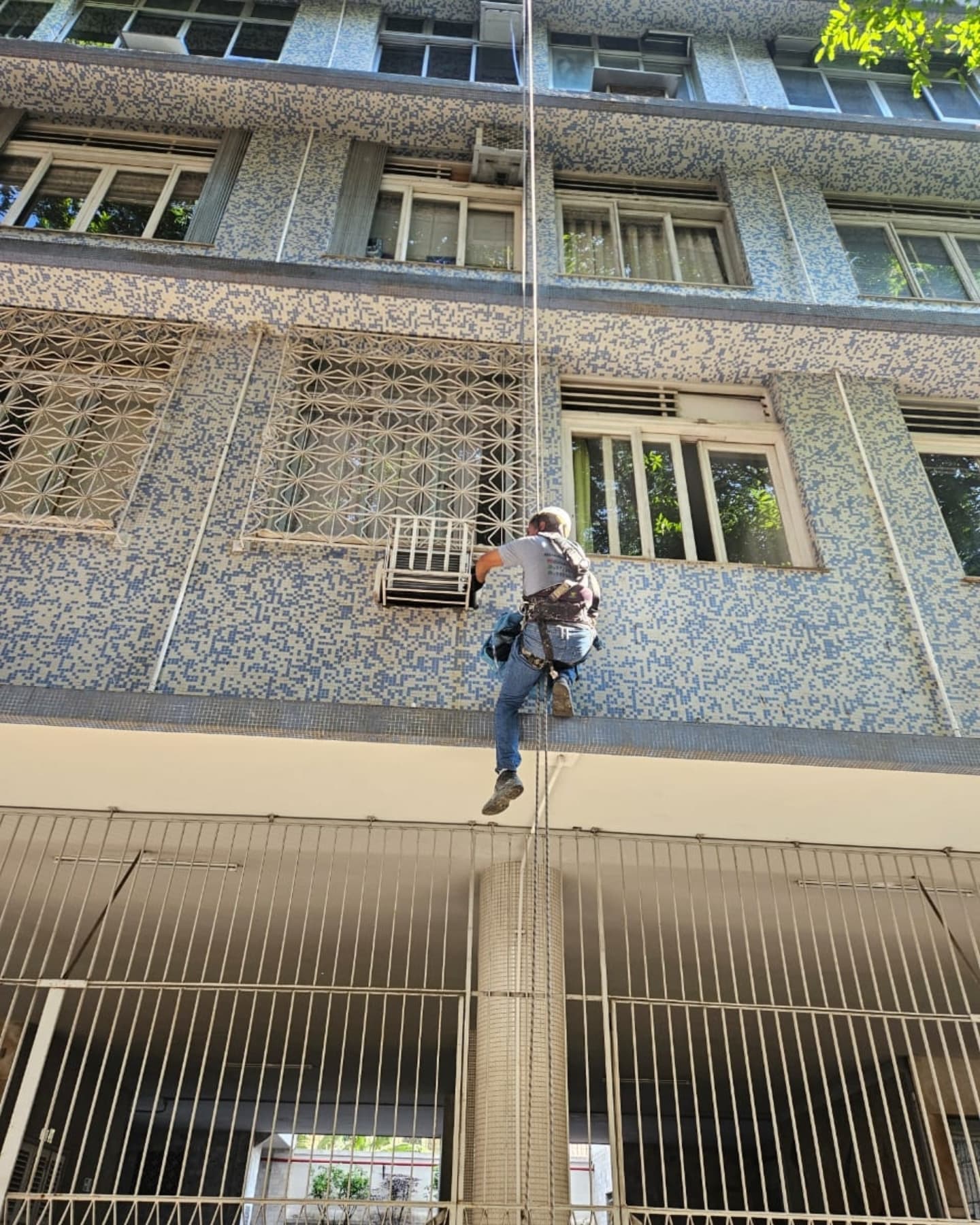 Profissional em rapel trabalhando na fachada de um edifício