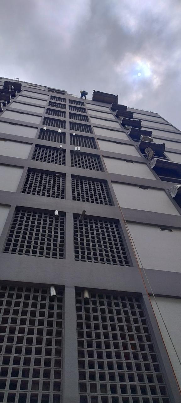 Fachada de edifício recuperada vista de baixo com profissional em rapel