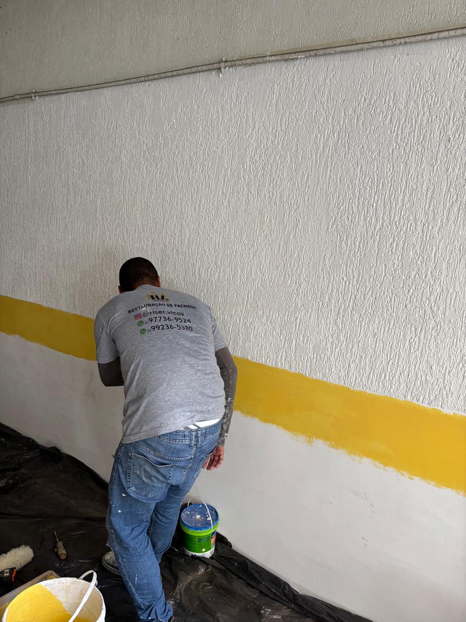Profissional da RL Serviços aplicando faixa amarela em parede